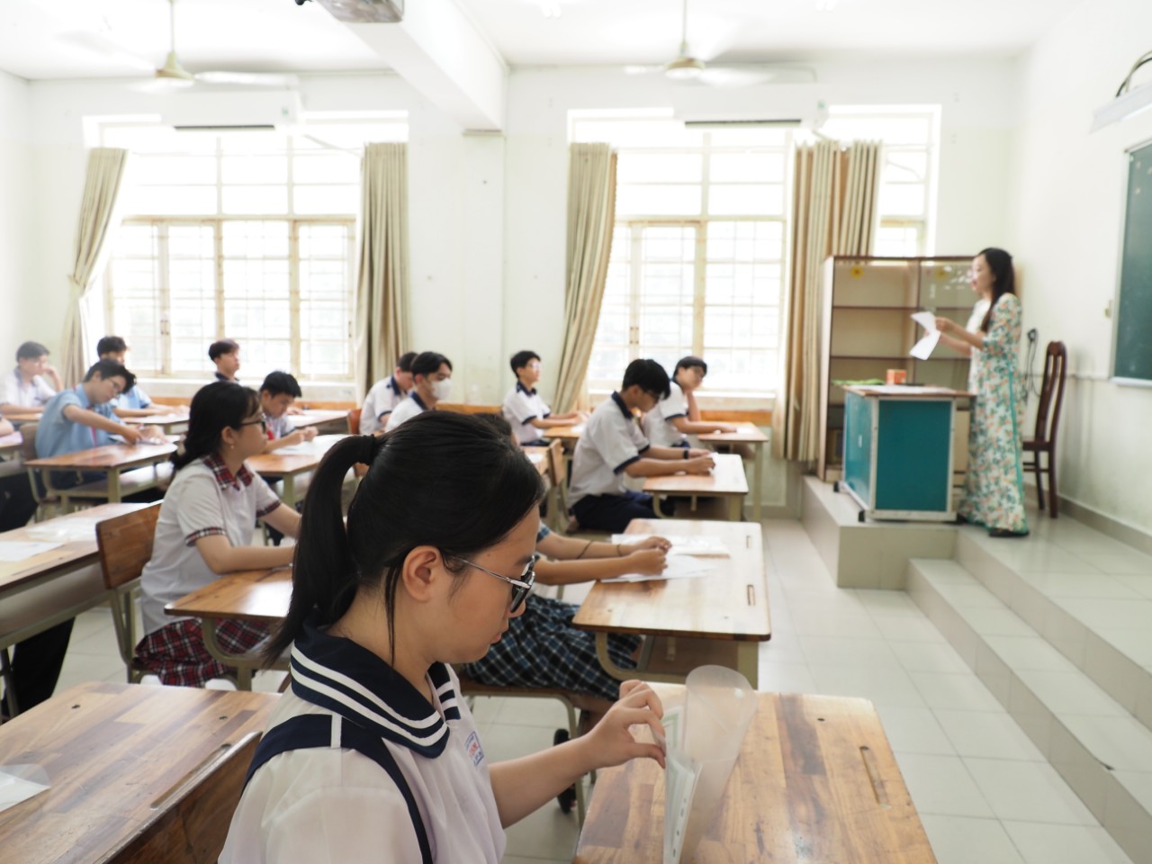 Cán bộ coi thi phổ biến quy chế thi và hướng dẫn thí sinh kiểm tra thông tin trên phiếu báo dự thi tại điểm thi THCS Lê Văn Tám (Ảnh: Tâm Thu).